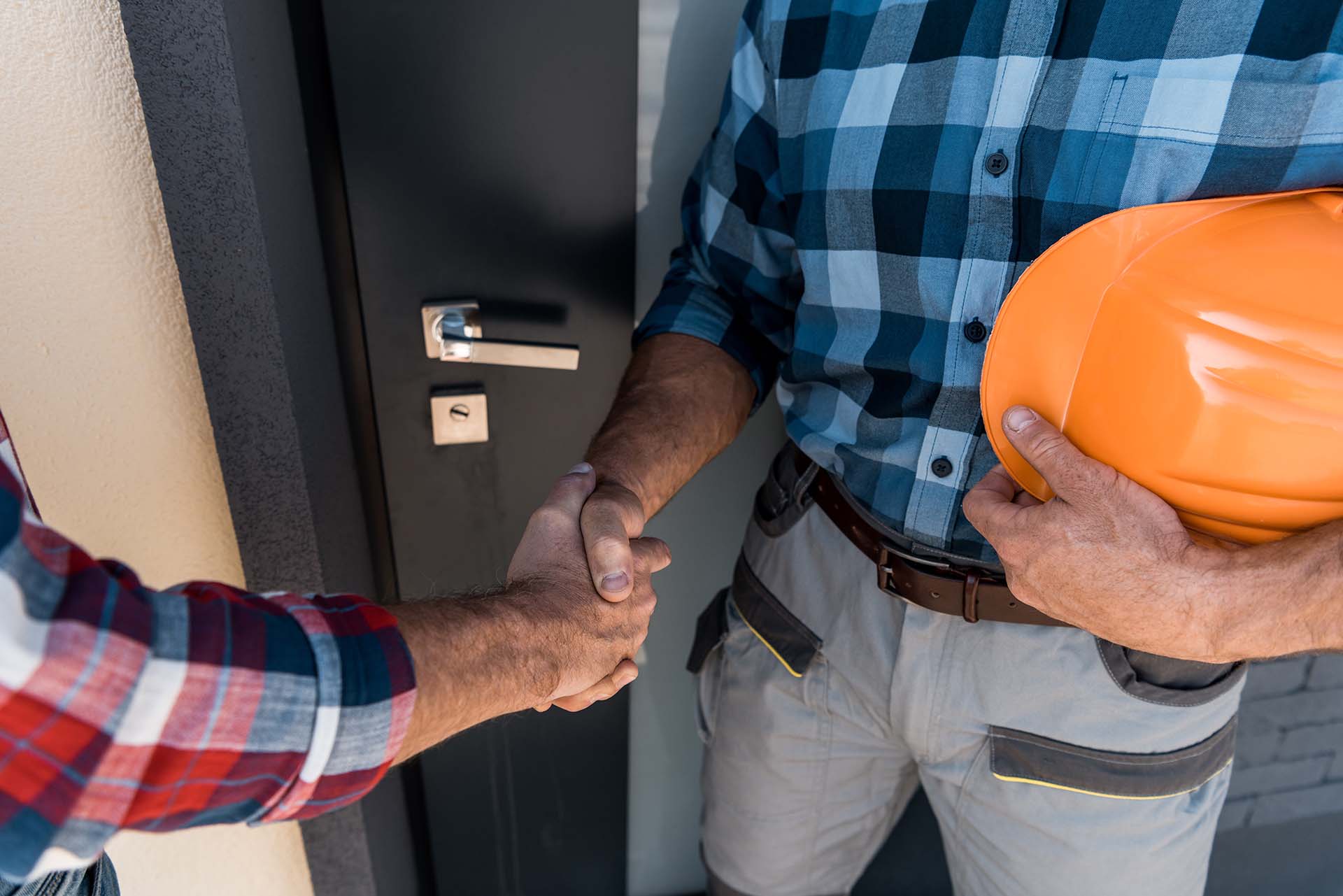 cropped view of builders shaking hands while standing near door