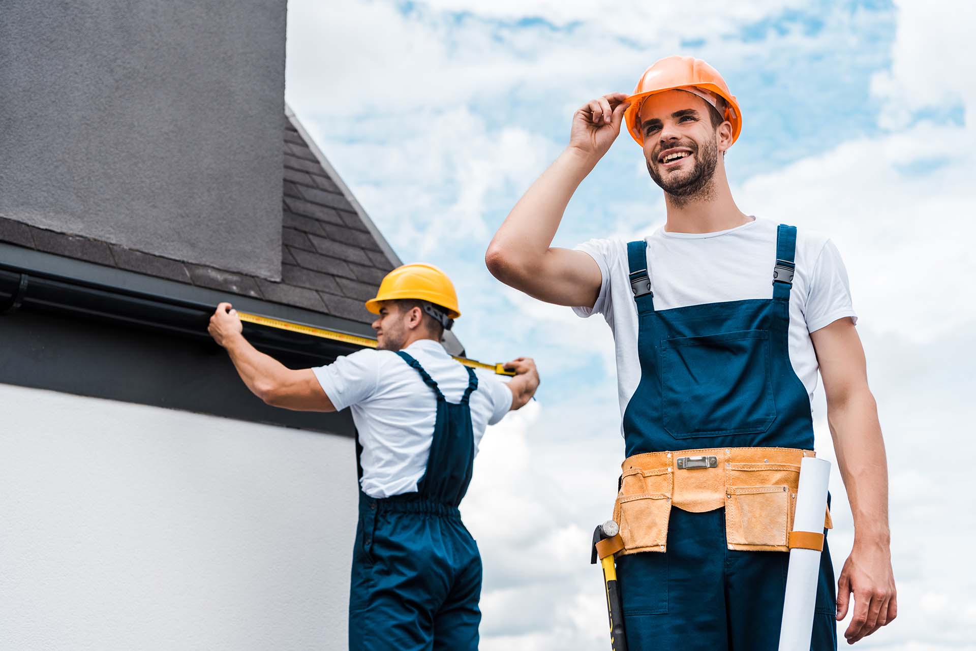 selective focus of happy repairman touching helmet and smiling near coworker